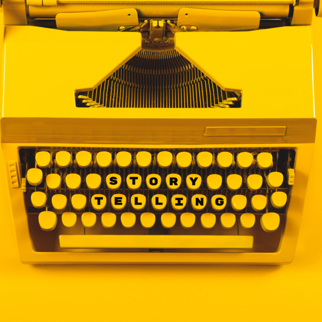 Overhead shot of bright, yellow typewriter with letter keys in the center spelling out "STORYTELLING"